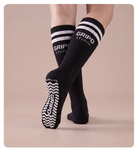 Flow Lite knee-high grip sock, black with white stripes, showing the moulded silicone sole