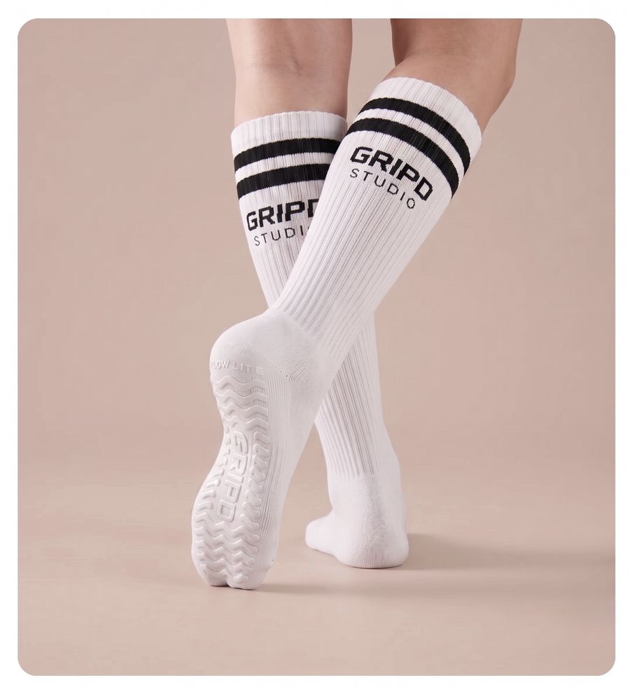 Flow Lite knee-high grip sock, white with black stripes, showing the moulded silicone sole