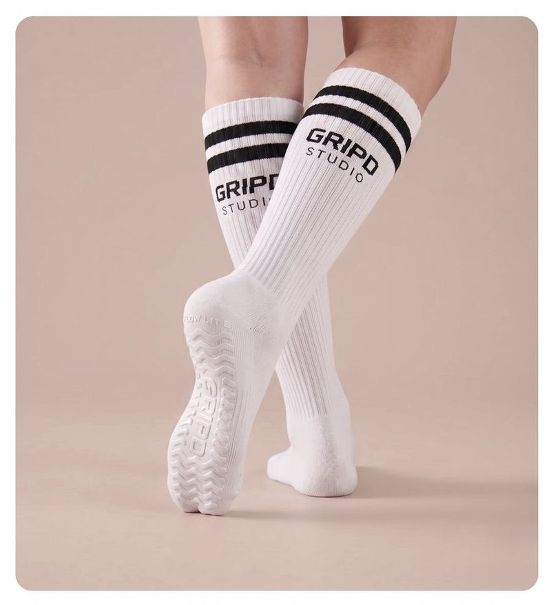 Flow Lite knee-high grip sock, white with black stripes, showing the moulded silicone sole